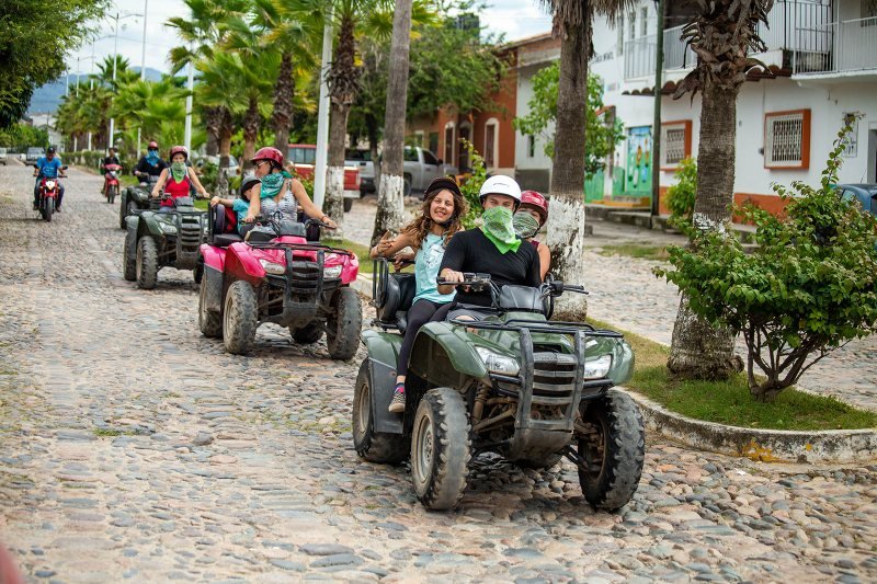 ATV riders on a cobblestone street of a Puerto Vallarta hillside neighbourhood